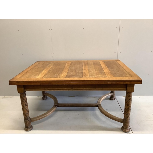 63 - An early 20th century golden oak draw leaf dining table on carved underframe, width 153cm, 227cm ext... 