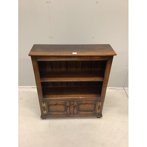 1015 - A reproduction 18th century style oak two shelf open bookcase, the base fitted with fielded panelled... 