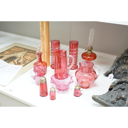 1335 - A quantity of cranberry glassware to include pair of vases with trailed decoration, jugs and an oil ... 