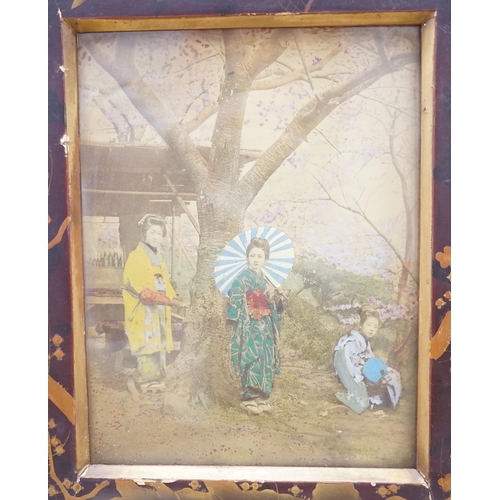 1337 - A pair of Japanese lacquered frames housing hand coloured photographs of women wearing kimonos, over... 