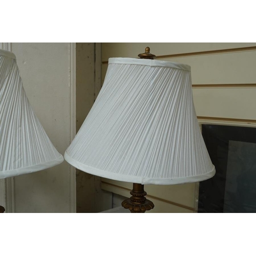 1432 - A pair of gilt resin table lamps with white shades, 76cm high. Condition - fair to good.