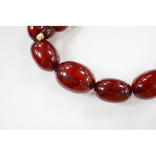 1919 - A single strand graduated oval simulated cherry amber bead necklace, 38cm, gross weight 41 grams. Co... 