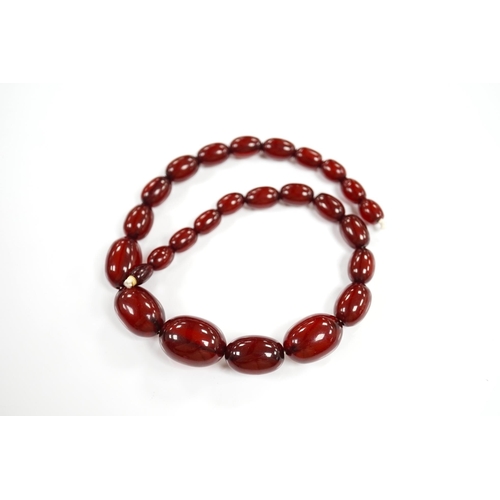 1919 - A single strand graduated oval simulated cherry amber bead necklace, 38cm, gross weight 41 grams. Co... 