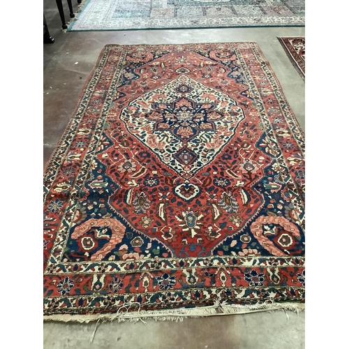 100 - A North West Persian brick red ground carpet, 320 x 178cm. Condition - poor to fair