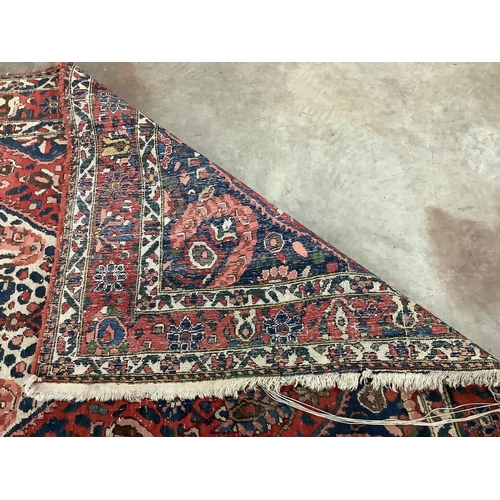 100 - A North West Persian brick red ground carpet, 320 x 178cm. Condition - poor to fair