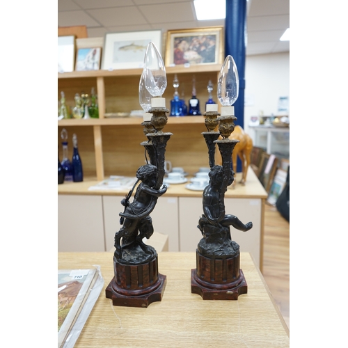 387 - A pair of French bronze cupid twin candelabra with leaf shaped twin arms upon rouge marble fluted co... 