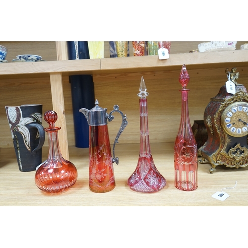 409 - A collection of cranberry glassware comprising three decanters with stoppers and a silver plate moun... 