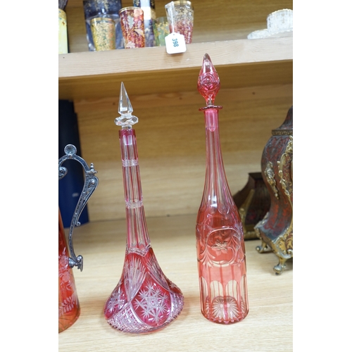 409 - A collection of cranberry glassware comprising three decanters with stoppers and a silver plate moun... 