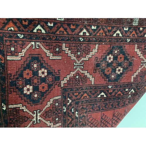 1002 - A Belouch red ground carpet, approximately 250cm x 160cm. Condition - fair to good