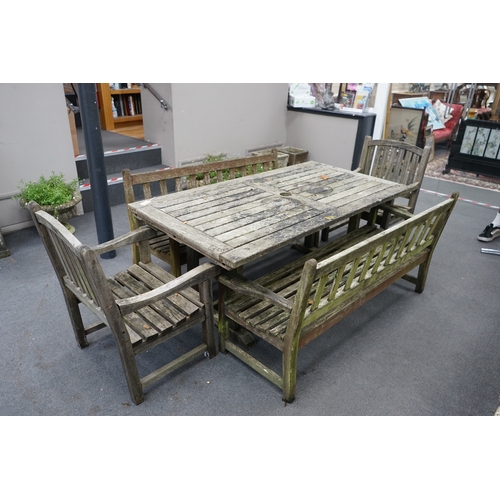 1173 - A weathered teak extending garden table, with pair of matching slatted benches and two elbow chairs,... 