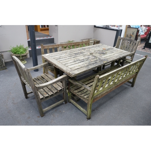 1173 - A weathered teak extending garden table, with pair of matching slatted benches and two elbow chairs,... 