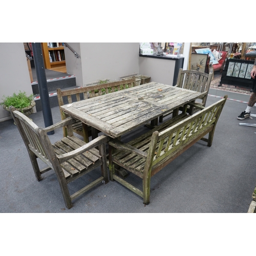 1173 - A weathered teak extending garden table, with pair of matching slatted benches and two elbow chairs,... 