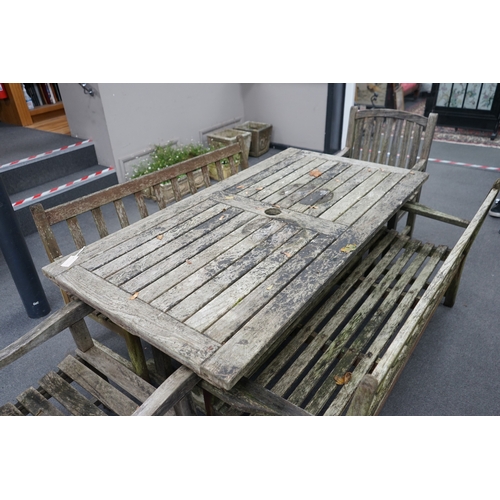 1173 - A weathered teak extending garden table, with pair of matching slatted benches and two elbow chairs,... 