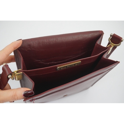 1251 - A Must de Cartier lady's leather shoulder bag in bordeaux, with dust bag