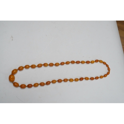 1914 - A single strand graduated oval amber bead necklace, 62cm, gross weight 34 grams. Condition - poor to... 