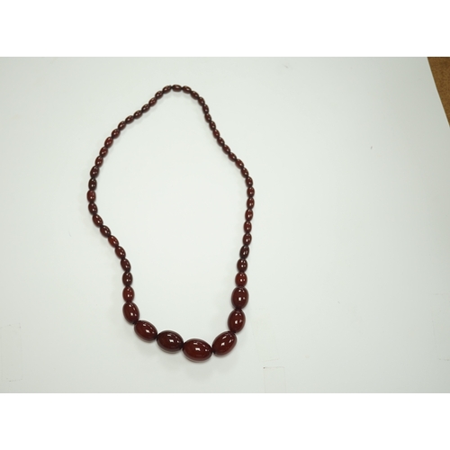 1916 - A single strand graduated oval simulated cherry amber bead necklace, 74cm, gross weight 71 grams. Co... 