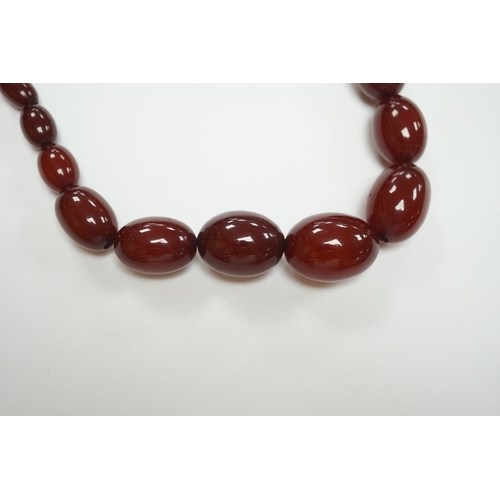 1916 - A single strand graduated oval simulated cherry amber bead necklace, 74cm, gross weight 71 grams. Co... 