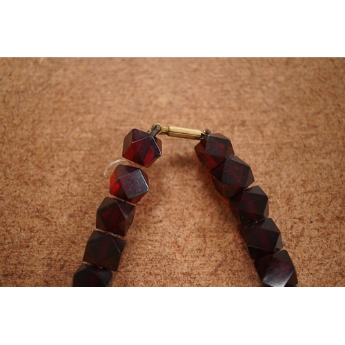 1917 - A single strand part facetted simulated cherry amber and part facet paste set necklace, (approx. 30 ... 