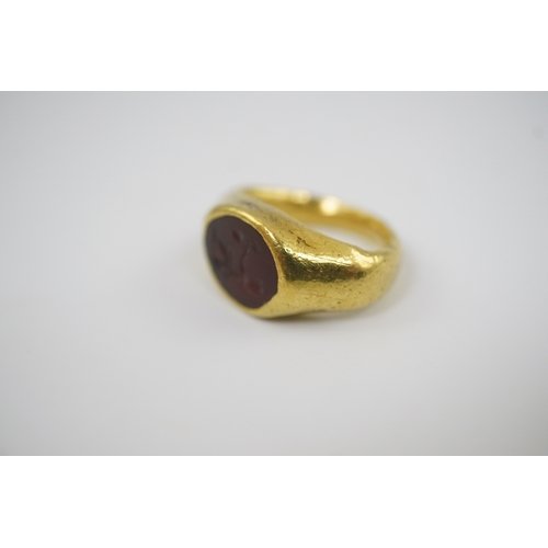 117 - A Roman gold and intaglio set ring, carved with a seated figure, shank misshapen, gross weight 9.5 g... 