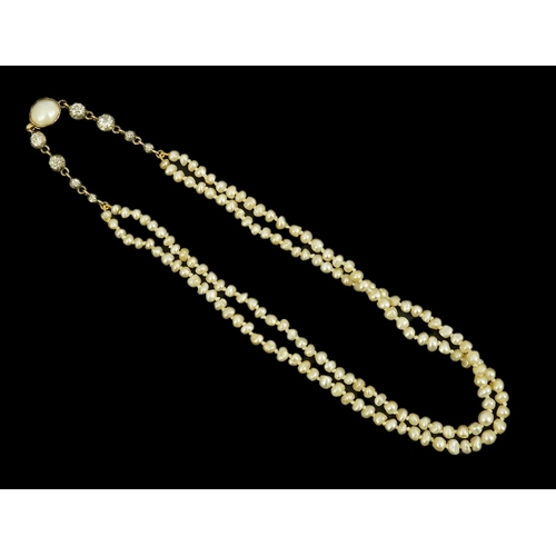 134 - An antique twin strand baroque pearl necklace, with pearl set gold clasp bordered with single chain ... 