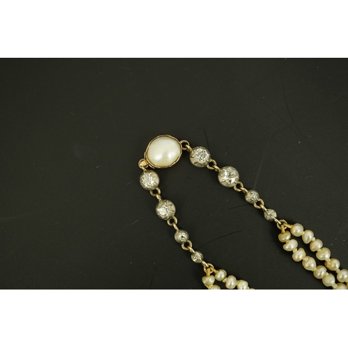 134 - An antique twin strand baroque pearl necklace, with pearl set gold clasp bordered with single chain ... 