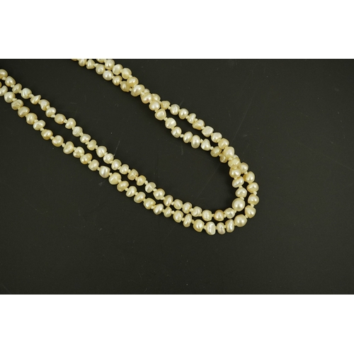 134 - An antique twin strand baroque pearl necklace, with pearl set gold clasp bordered with single chain ... 