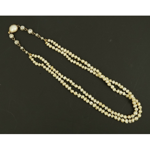 134 - An antique twin strand baroque pearl necklace, with pearl set gold clasp bordered with single chain ... 