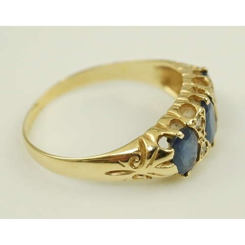 163 - An Edwardian 15ct gold and three stone oval cut sapphire set half hoop ring, with diamond chip space... 