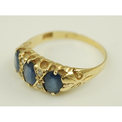 163 - An Edwardian 15ct gold and three stone oval cut sapphire set half hoop ring, with diamond chip space... 