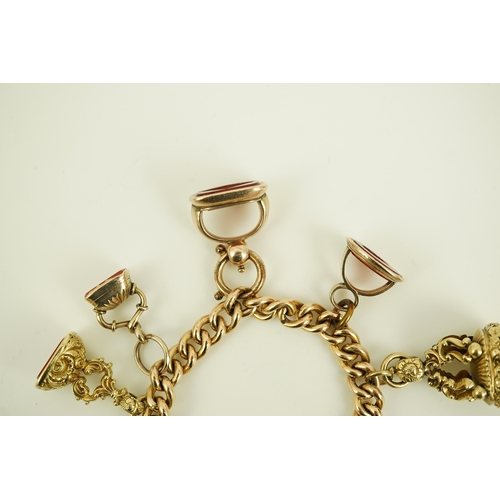 165 - An Edwardian 15ct gold curb link charm bracelet with heart shaped padlock clasp, hung with six assor... 