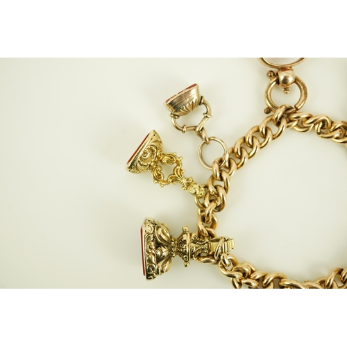 165 - An Edwardian 15ct gold curb link charm bracelet with heart shaped padlock clasp, hung with six assor... 