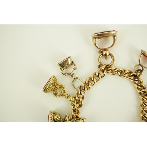 165 - An Edwardian 15ct gold curb link charm bracelet with heart shaped padlock clasp, hung with six assor... 