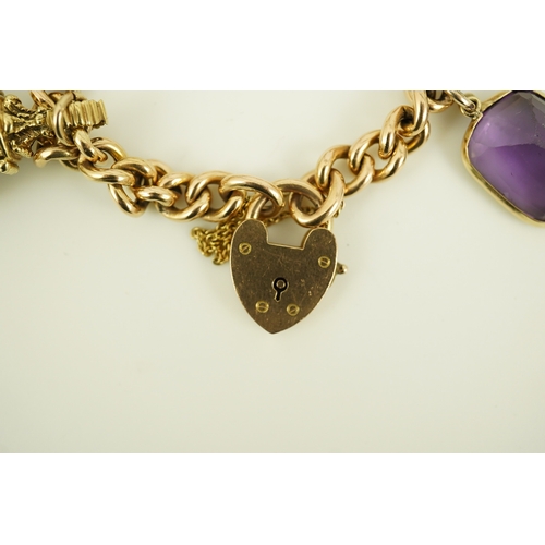 165 - An Edwardian 15ct gold curb link charm bracelet with heart shaped padlock clasp, hung with six assor... 