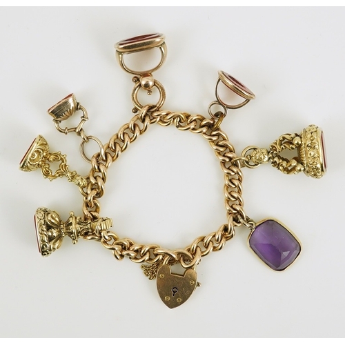 165 - An Edwardian 15ct gold curb link charm bracelet with heart shaped padlock clasp, hung with six assor... 