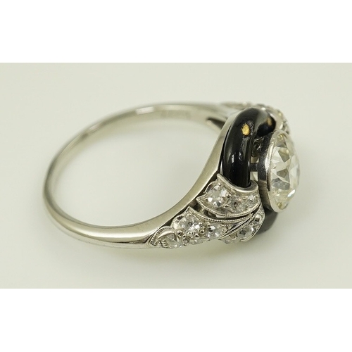 185 - An Art Deco platinum black enamel and diamond set ring, with diamond set shoulders, the central ston... 