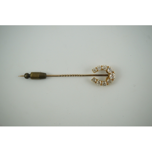 186 - An early 20th century gold and nine stone graduated old cut diamond set horseshoe stick pin, 68mm, g... 