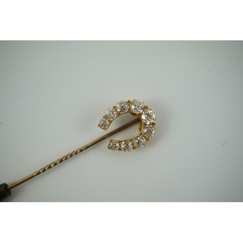 186 - An early 20th century gold and nine stone graduated old cut diamond set horseshoe stick pin, 68mm, g... 