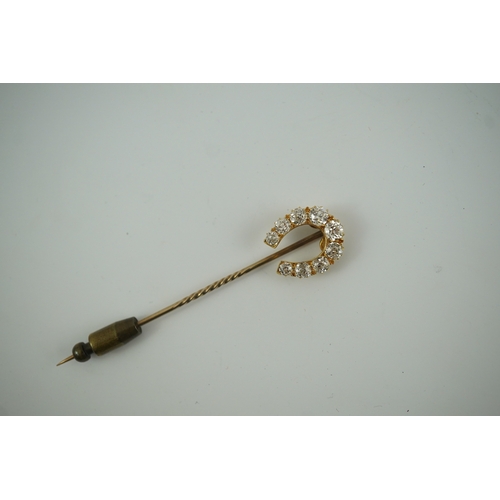 186 - An early 20th century gold and nine stone graduated old cut diamond set horseshoe stick pin, 68mm, g... 