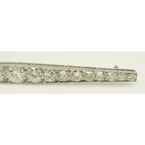 187 - A 1920's platinum? and nineteen millegrain set graduated diamond bar brooch, 59mm, gross weight 4.6 ... 