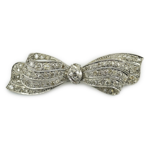 195 - A 1940's platinum? and diamond cluster set ribbon bow brooch, with central old mine cut stone, 49mm,... 