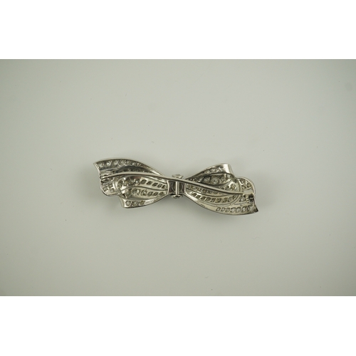 195 - A 1940's platinum? and diamond cluster set ribbon bow brooch, with central old mine cut stone, 49mm,... 