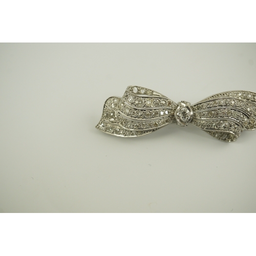 195 - A 1940's platinum? and diamond cluster set ribbon bow brooch, with central old mine cut stone, 49mm,... 