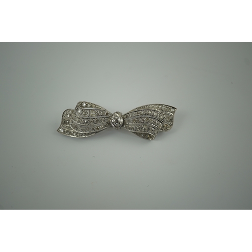 195 - A 1940's platinum? and diamond cluster set ribbon bow brooch, with central old mine cut stone, 49mm,... 