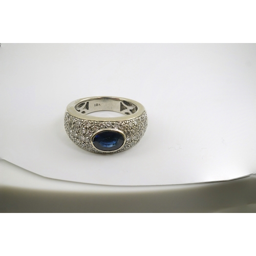 241 - A modern 18k white gold and gypsy set single stone oval cut sapphire set ring, with pave diamond set... 