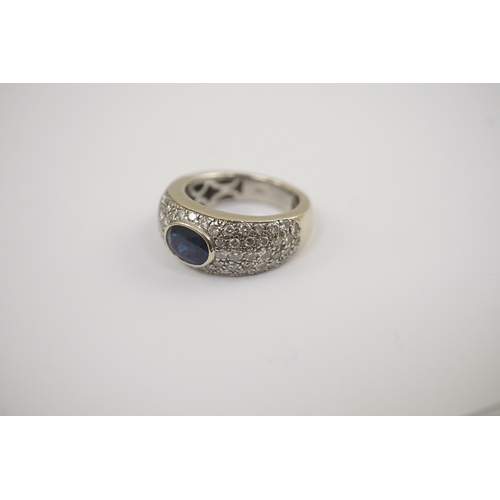 241 - A modern 18k white gold and gypsy set single stone oval cut sapphire set ring, with pave diamond set... 