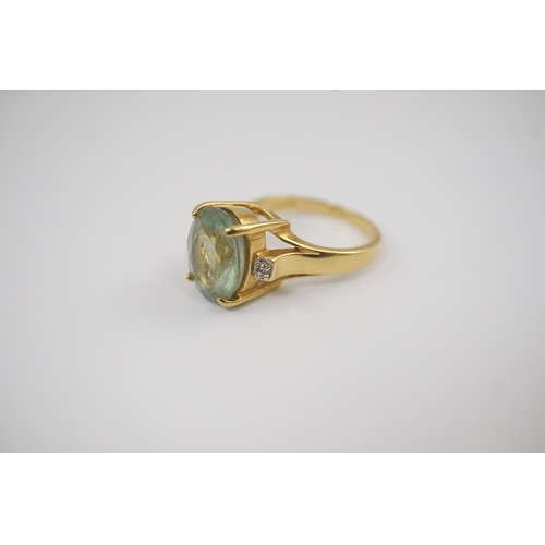 246 - A modern 18ct gold and oval cut pale green tourmaline set dress ring, with two stone diamond chip se... 