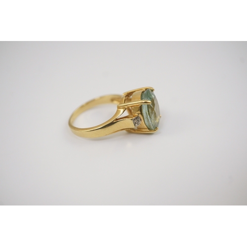 246 - A modern 18ct gold and oval cut pale green tourmaline set dress ring, with two stone diamond chip se... 