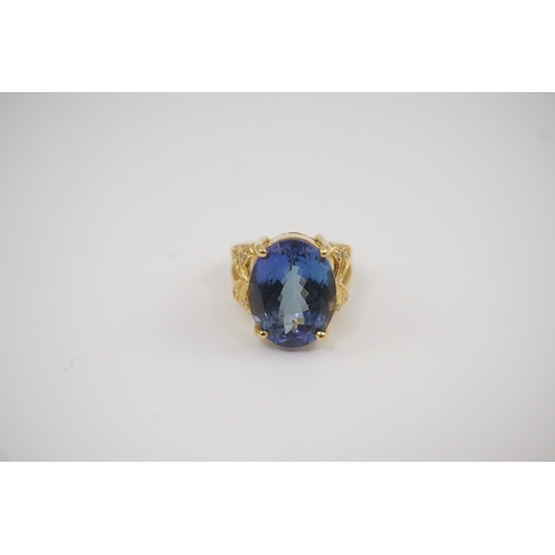 248 - A modern 18ct gold and single stone oval cut tanzanite set dress ring, with eight stone diamond chip... 