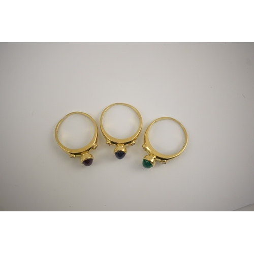 252 - A suite of three modern 18k gold and gem set rings, each set with a cabochon emerald, sapphire or ru... 