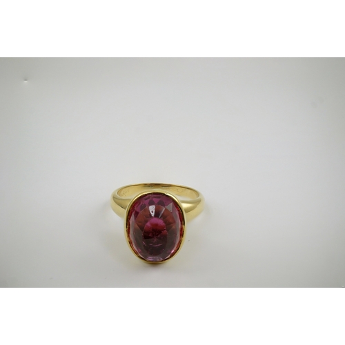 257 - A modern 18k gold and single stone fancy oval cut deep pink tourmaline set dress ring, signed Asprey... 